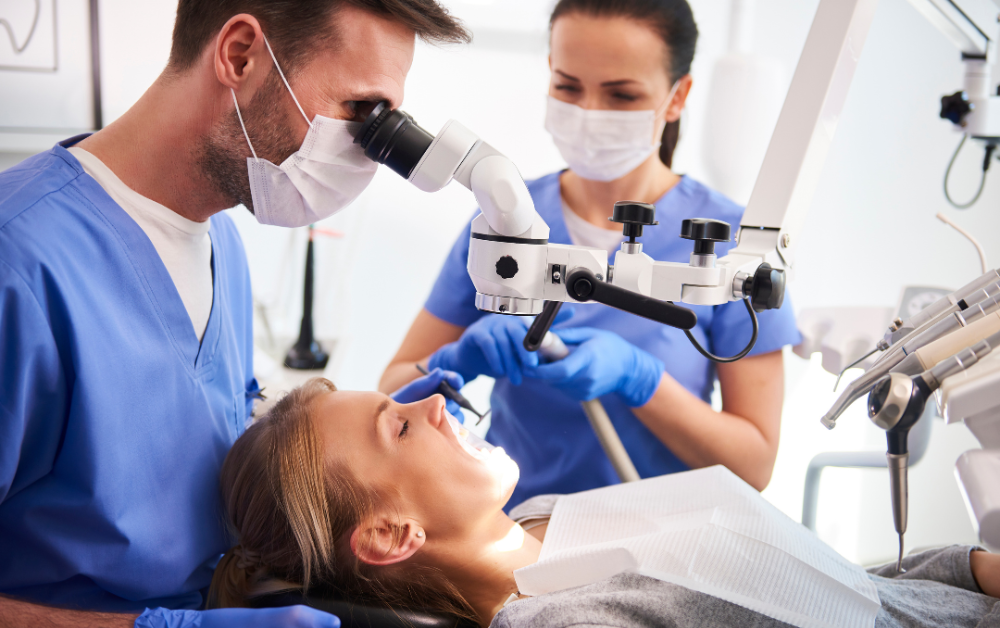 Zubár ošetruje pacienta za pomoci dentálneho mikroskopu